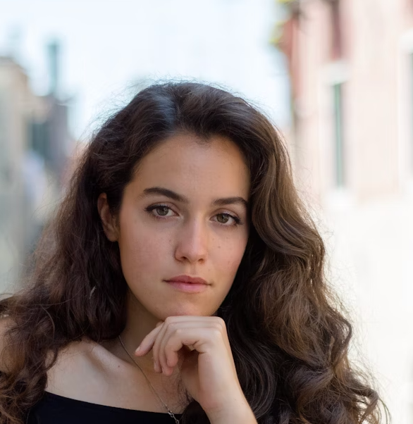 Woman with curly dark hair looking at the camera outdoors